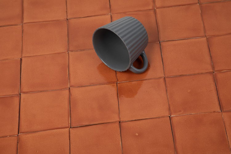 Quadratische Wandfliesen in Terracotta mit einer grauen Tasse