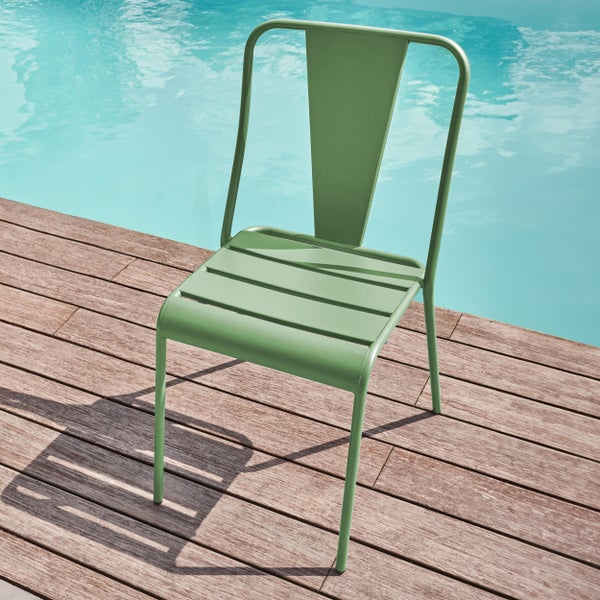 Grüner Gartenstuhl aus Metall auf einer Holzterrasse an einem Pool.