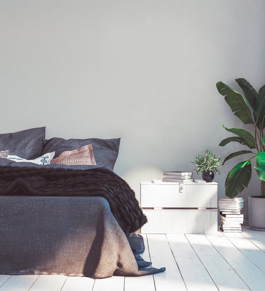 Schlafzimmer mit Bett, Nachttisch, Pflanzen und Dekorationsartikeln für eine gemütliche Atmosphäre.