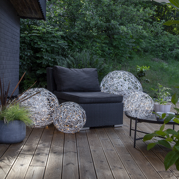 Gartenszene mit Rattansessel und dekorativen Kugelleuchten aus Metalldraht