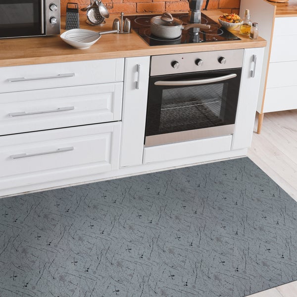 Grauer Teppich vor einer Küchenzeile mit weißen Schränken und Elektroherd.