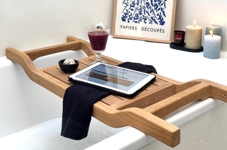 Szene mit Holzbadewannenablage, Tablet, Getränk, Kerzen und Dekoration auf einer Badewanne
