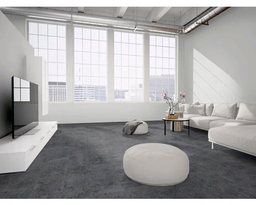 Moderner Wohnraum im Industrie-Stil mit großflächigem dunklem Boden in Betonoptik, hellem Sofa und großen Fenstern.