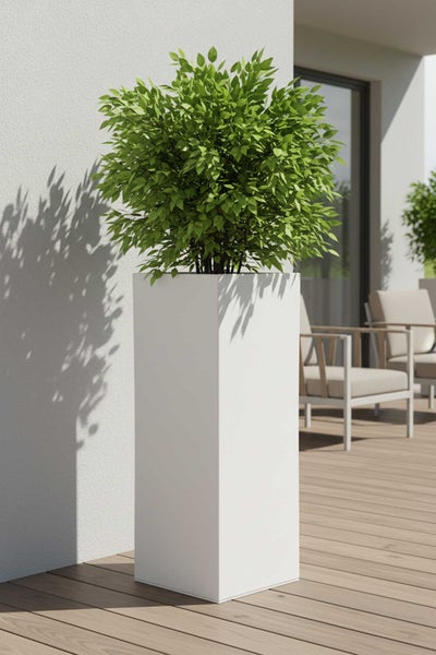 Hoher, quadratischer Pflanzkübel in Weiß mit einer grünen Pflanze auf einer modernen Holzterrasse neben Gartenmöbeln.