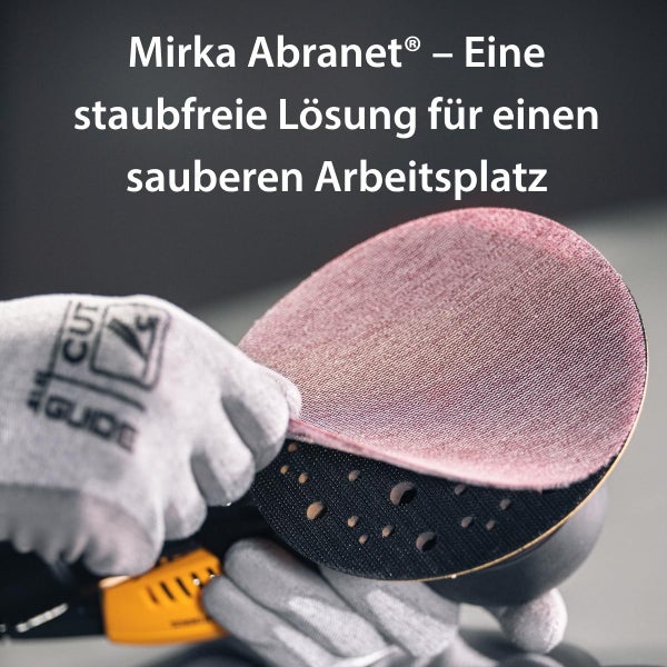 Eine Person mit Arbeitshandschuhen beim Befestigen eines runden Mirka Abranet Schleifgitters auf einem Exzenterschleifer.