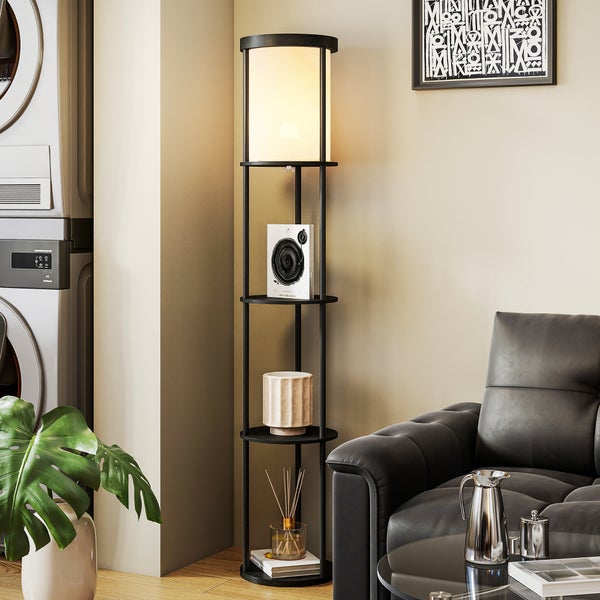 Moderne Stehleuchte aus schwarzem Metall mit integrierten Regalböden und weißem Schirm in einem Wohnzimmer neben einem Ledersessel.