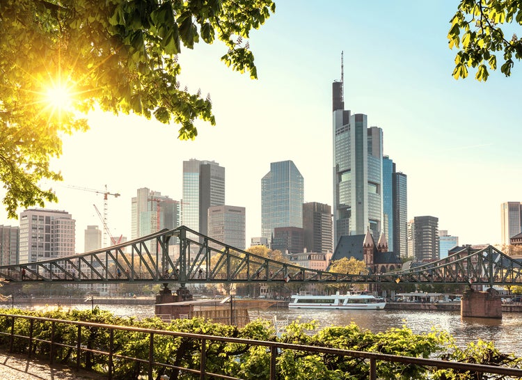 Skyline von Frankfurt am Main mit dem Eisernen Steg und Wolkenkratzern bei strahlendem Sonnenschein.