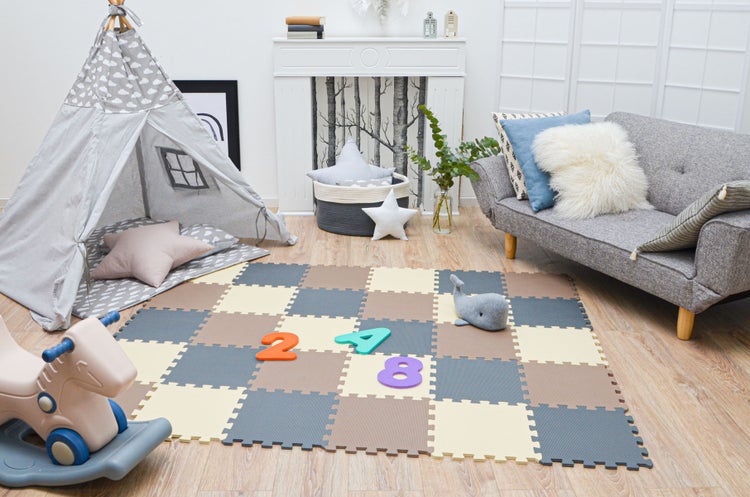 Helles Kinderzimmer mit Puzzlematte aus Schaumstoff, Tipi-Spielzelt, Schaukelpferd und Sofa.