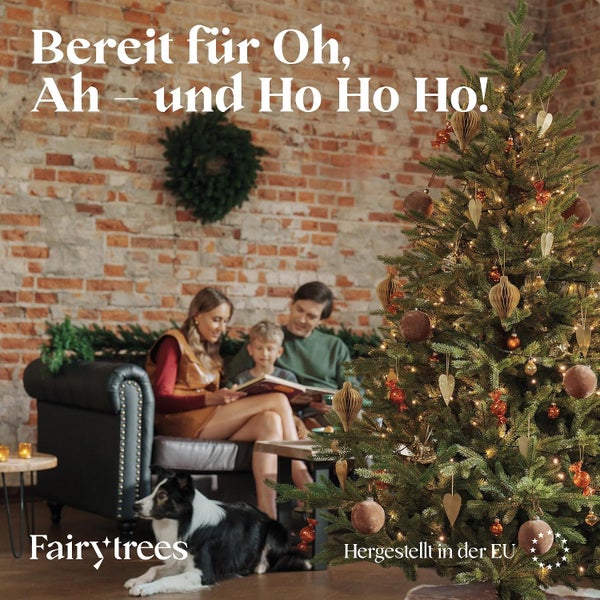 Familie mit Hund vor einem dekorierten Weihnachtsbaum in einem Wohnzimmer mit Backsteinwand. Fairy Trees Logo und Hergestellt in der EU Siegel.