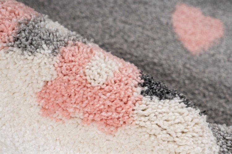 Nahaufnahme eines flauschigen Kinderteppichs mit Herzmotiv und hochflorigem Textilmaterial.