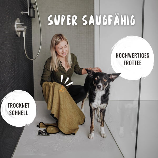 Frau trocknet Hund mit saugfähigem Frotteehandtuch im Badezimmer