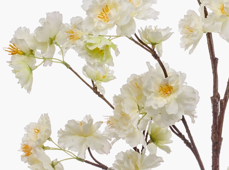 Künstlicher Dekozweig mit weißen Blüten und gelben Staubbeuteln.