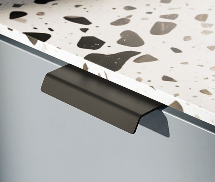 Moderner Griff für Küchenschublade aus Metall an einer Front unter einer Arbeitsplatte mit Terrazzo Optik