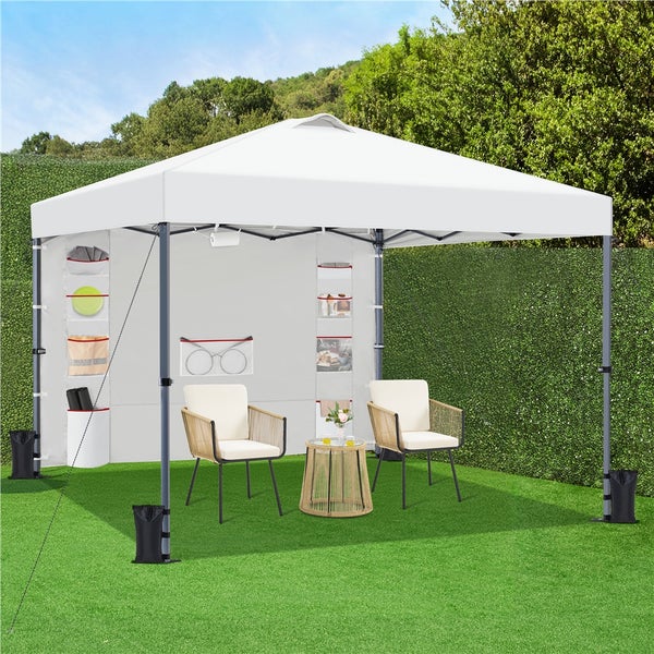 Weißes Gartenzelt mit Staufächern, Tisch und zwei Stühlen auf einer Rasenfläche