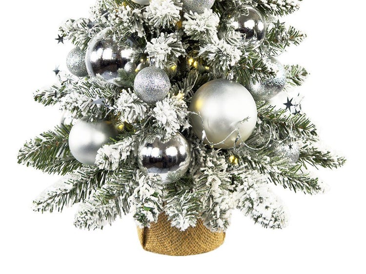Künstlicher Weihnachtsbaum mit Schnee, Kugeln und Beleuchtung im Jutesack als festliche Weihnachtsdekoration für Tisch und Innenbereich.