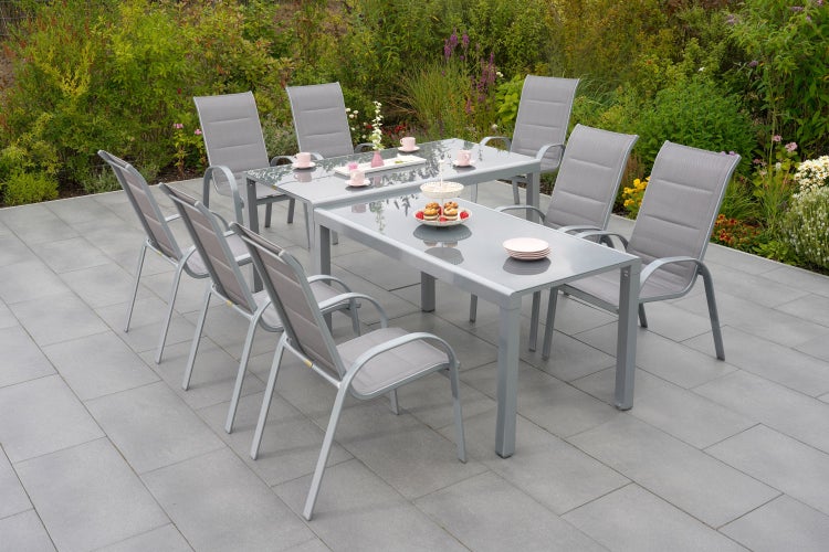 Gartenszene mit zwei Esstischen und acht Stühlen auf einer Terrasse