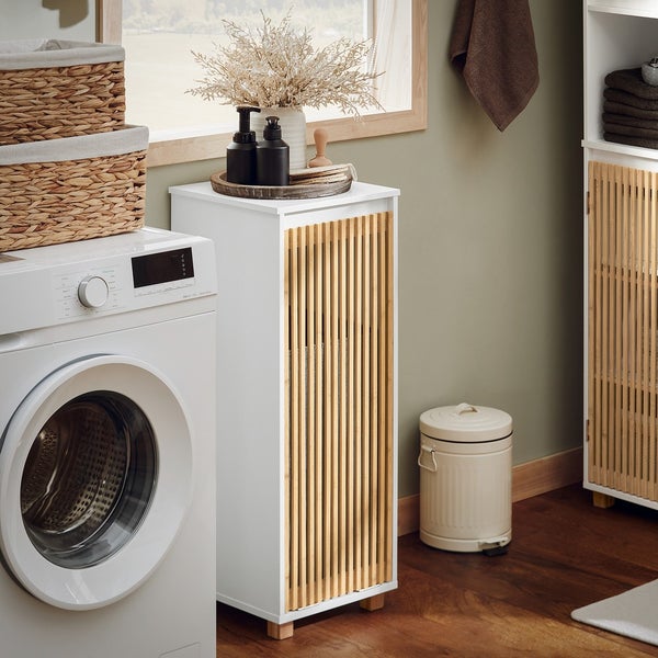 Badezimmer mit Waschmaschine, Wäschesammlern, Waschbeckenunterschrank, Abfalleimer und Dekoration