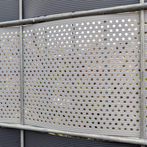 Graue Lärmschutzwand mit Lochmuster und Metallrahmen