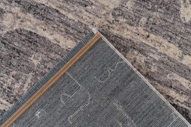 Detailansicht eines grau-beigen Teppichs mit abstraktem Muster, zeigt die Oberseite und die strukturierte, gewebte Rückseite.