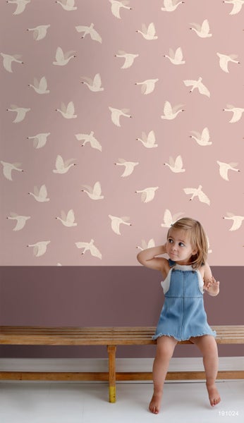 Zimmer mit Tapete mit Schwanmuster und sitzendem Kind auf einer Holzbank.