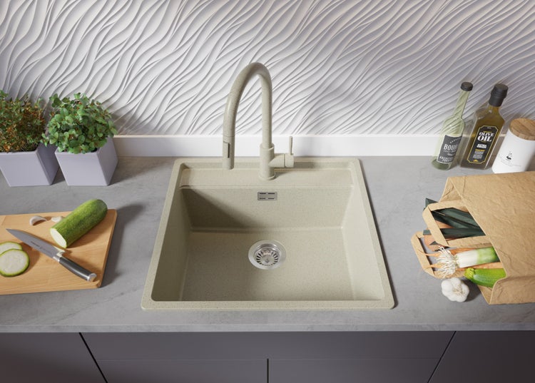 Küchenspüle mit Armatur, Gemüse und Küchenutensilien auf der Arbeitsplatte.