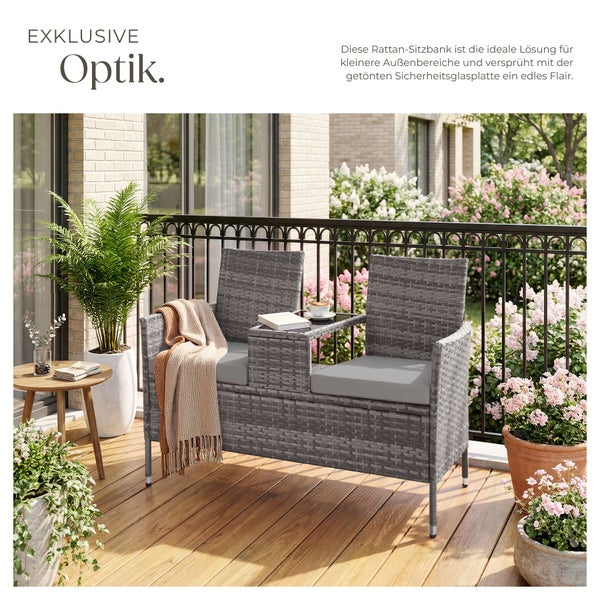 Moderne Rattan-Sitzbank für den Balkon mit integriertem Tisch in der Mitte, grauen Sitzkissen und einer Decke auf einem Holzdeck.