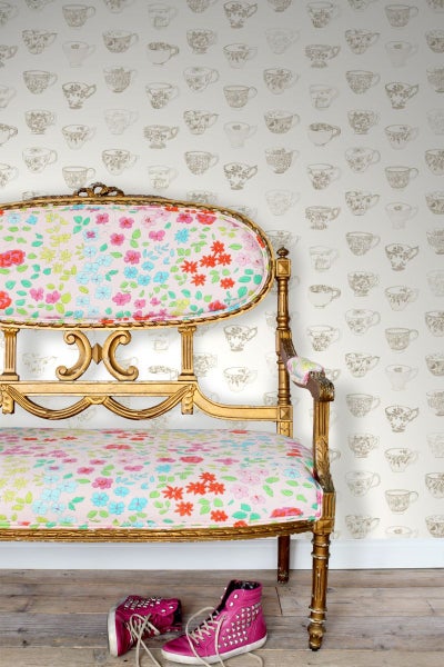 Dekoratives Sofa mit floralem Muster und Paar rosa Turnschuhe