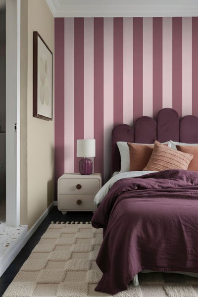 Modernes Schlafzimmer mit gestreifter Tapete, Bett mit bogenförmigem Kopfteil, Bettwäsche, Nachttisch und strukturiertem Teppich.