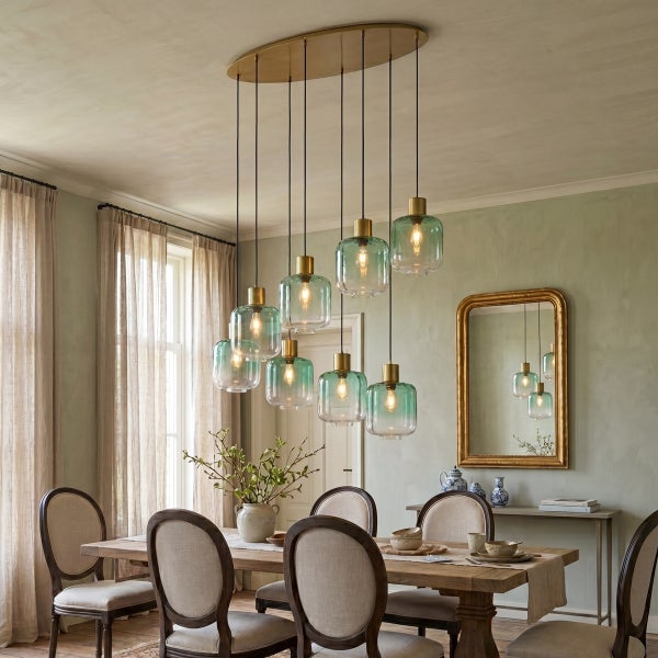 Esszimmer mit ovaler Pendelleuchte mit neun Glaskugeln über einem Holztisch mit Stühlen und Spiegel an der Wand.