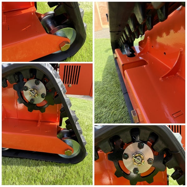 Detailaufnahme des Raupenfahrwerks eines Minidumpers mit Gummikette, Antriebsrad und Führungsrollen am orangefarbenen Metallrahmen.