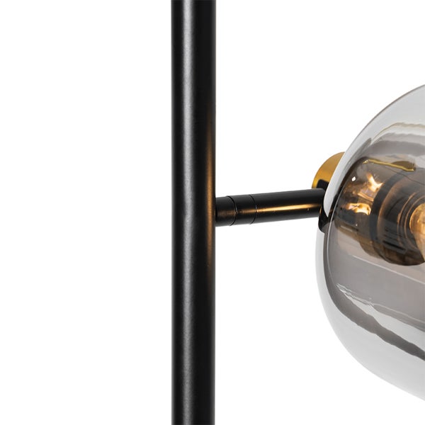 Nahaufnahme einer Leuchte mit schwarzem Metallgestell und gläsernem Lampenschirm.