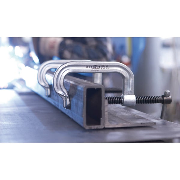 Zwei Schraubzwingen fixieren ein Metallprofil.