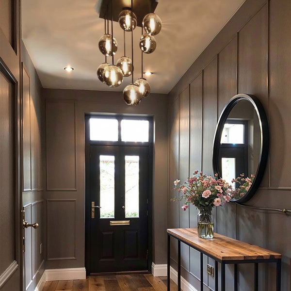 Eingangsbereich mit Pendelleuchte, Spiegel, Konsole und Holzboden.