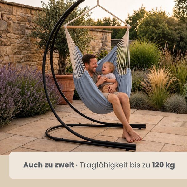 Ein Mann und ein Kind sitzen in einem Hängesessel mit Metallgestell im Garten. Das Gestell hat eine C-Form und ist für bis zu 120 Kilogramm ausgelegt.