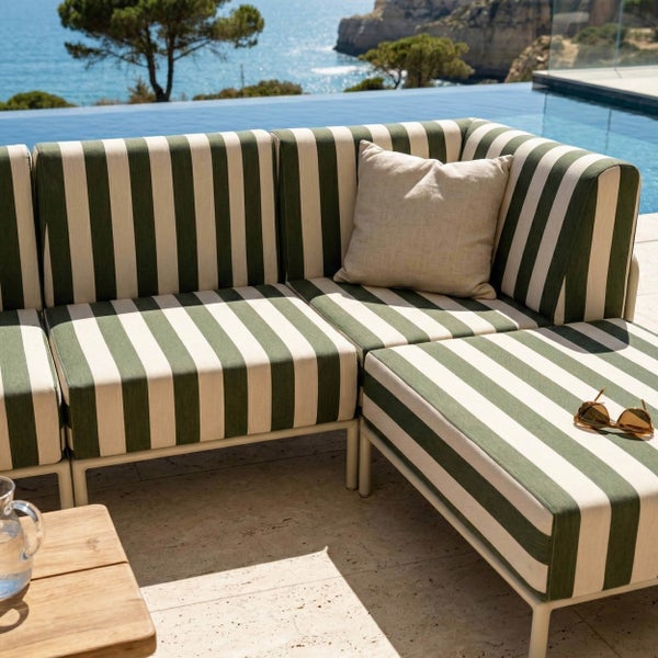 Moderne Gartenlounge mit gestreiftem Outdoor-Sofa auf einer hellen Terrasse neben einem Infinity-Pool mit Meerblick.