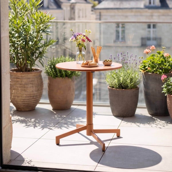 Runder Bistro-Tisch auf einem hellen Balkon mit Fliesenboden, Glasgeländer und verschiedenen Kübelpflanzen wie Lavendel und Sträuchern.