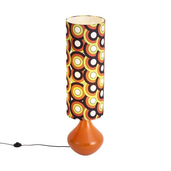 Retro-Tischlampe mit orangefarbenem Fuß und zylindrischem Textilschirm mit buntem Kreismuster im 70er-Jahre-Design.