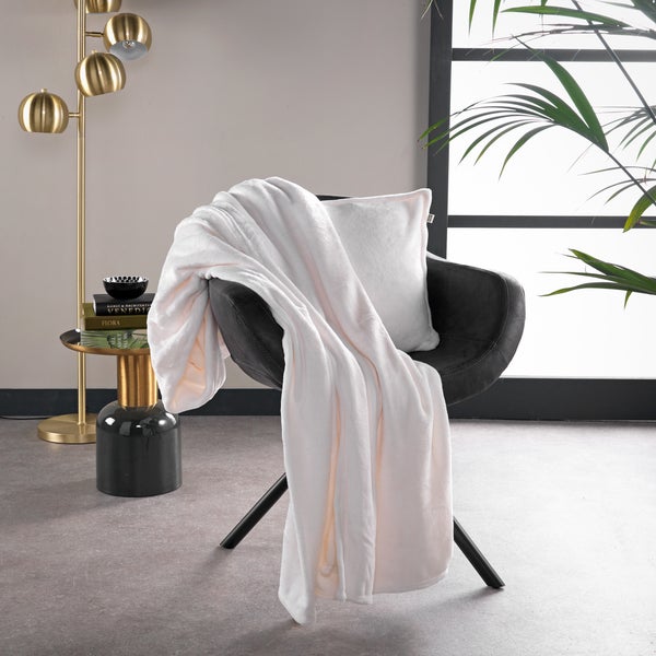 Dekoratives Wohnzimmer mit Sessel, Kissen und Kuscheldecke