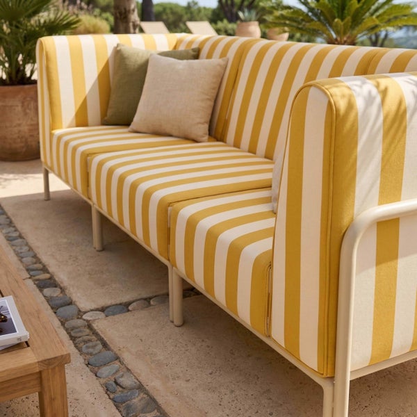 Outdoor-Lounge-Sofa mit gestreiftem Bezug und Zierkissen auf einer Steinterrasse mit Pflanzen.