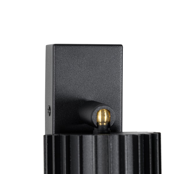 Wandleuchte mit schwarzer, rechteckiger Wandhalterung und geripptem Leuchtenkopf sowie goldfarbenem Gelenk.