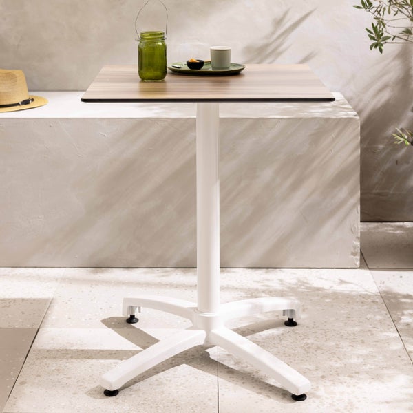 Quadratischer Bistrotisch mit Tischplatte in Holzoptik und weißem Metallgestell im Außenbereich.