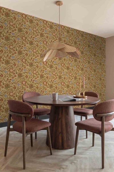 Modernes Esszimmer mit floral gemusterter Tapete, rundem Holztisch, gepolsterten Stühlen und einer Pendelleuchte im Blätter-Design.