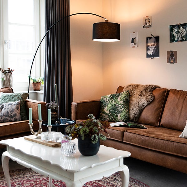 Wohnzimmer mit braunem Ledersofa, Bogenlampe und weißem Couchtisch