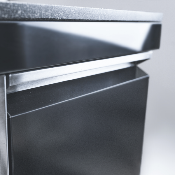 Detailansicht eines schwarzen Küchenschranks mit Arbeitsplatte in Steinoptik, glänzender Front und integrierter Griffleiste aus Metall.