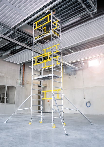 Rollgerüst mit einer Person bei der Arbeit in einer Industriehalle