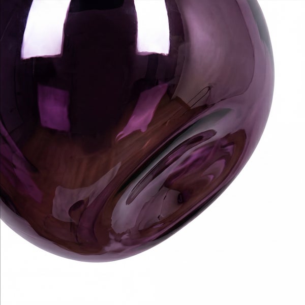Nahaufnahme einer glänzenden, lilafarbenen Weihnachtskugel mit stark reflektierender Oberfläche.