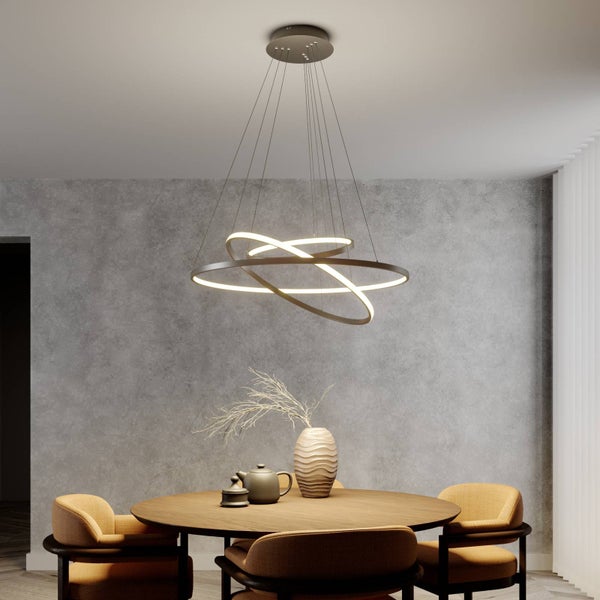 Moderne LED-Pendelleuchte mit drei ineinandergreifenden Ringen über einem runden Holztisch in einem Raum mit strukturierter Wand.
