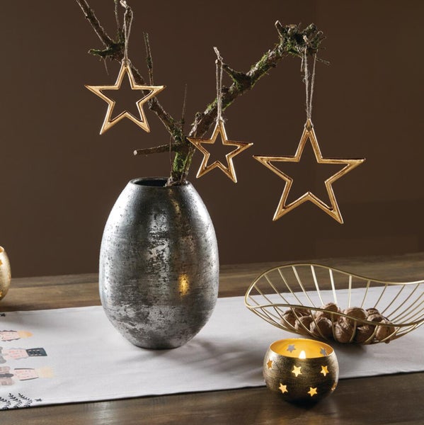 Weihnachtliche Tischdekoration mit einer metallischen Vase, drei hängenden Sternen an einem Ast, einer Drahtschale mit Nüssen und einem Windlicht.