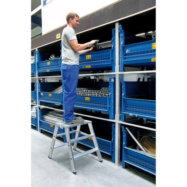 Mann auf Trittleiter, der in einem Lager arbeitet