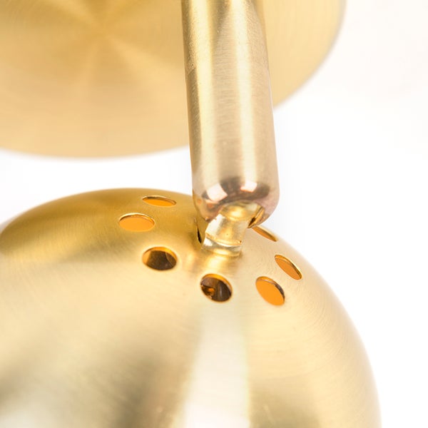 Detailaufnahme einer goldenen Wandleuchte mit perforiertem Lampenschirm